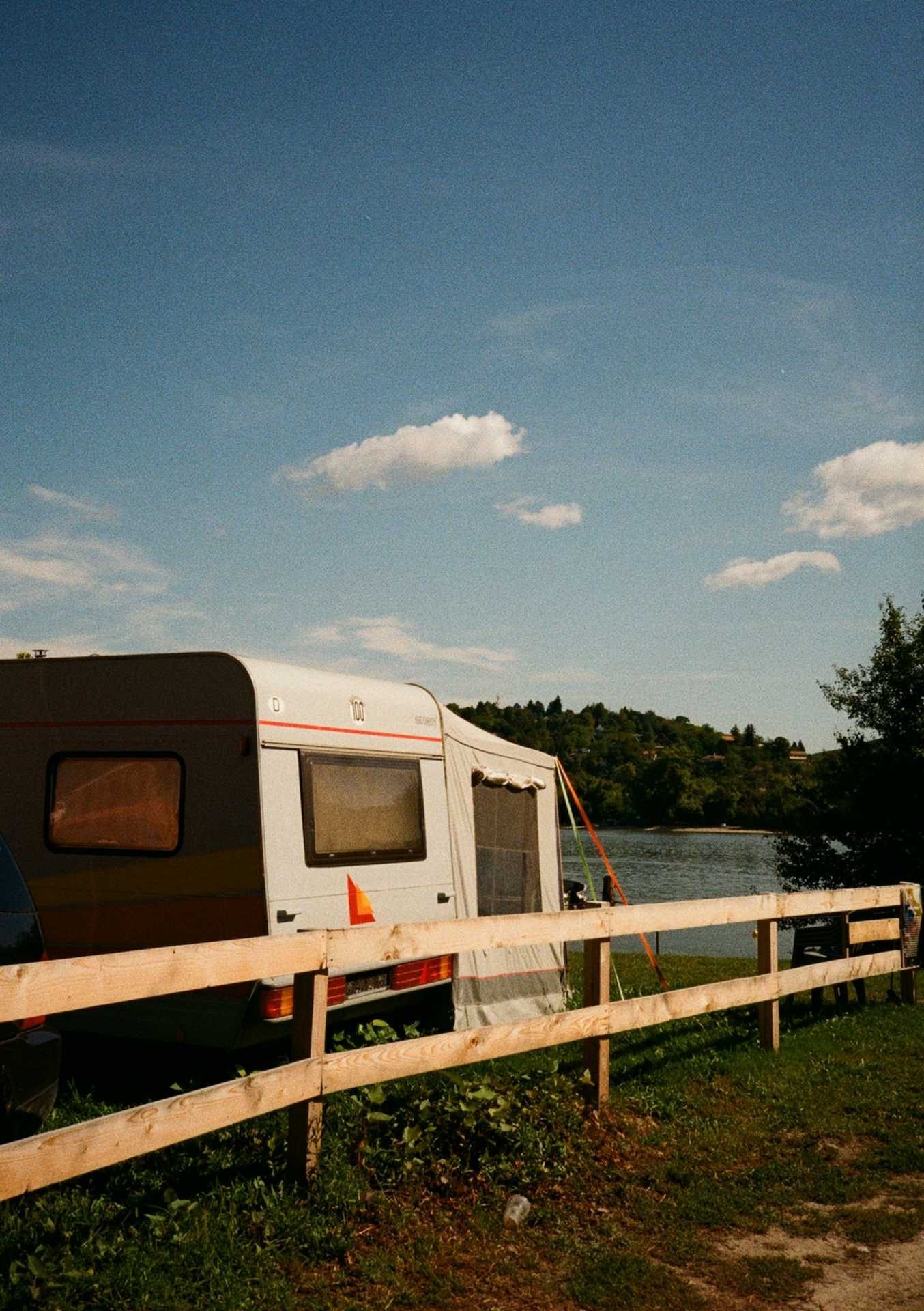 A caravan on a grass pitch by the fence
