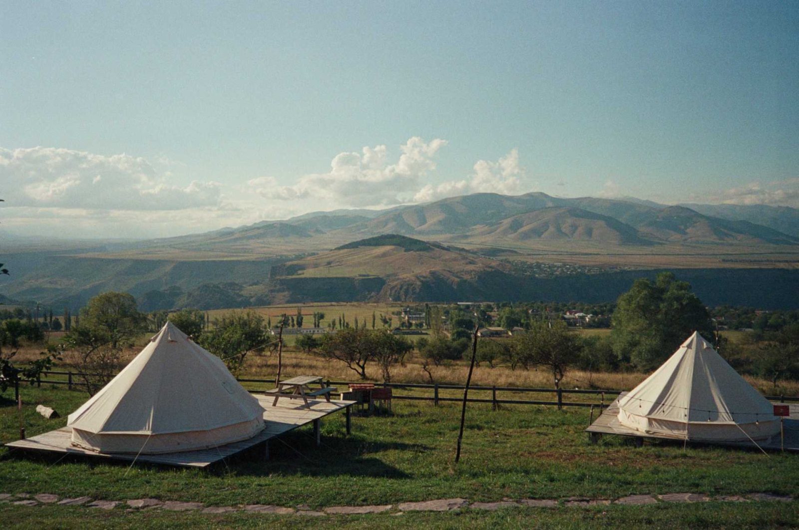 Two bell tents in the meadow below the hills
